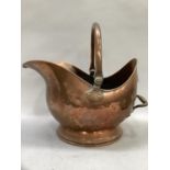 A copper coal scuttle on rimmed foot with swing handle and moulded handle to back measuring 43cm