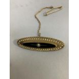 A Victorian mourning brooch in 15ct gold, set with seed pearls and onyx within a twisted wire