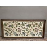 An early 20th century crewel work needlework panel worked as flowering tendrils in soft shades of