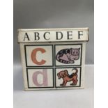 A vintage toy box in white cardboard with alphabet and play toys in orange, pink and black
