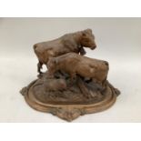 A 19th century Black Forest carved group of bull, cow and sheep upon a grassy knoll on an oval