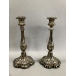 A pair of late 19th century candle sticks in silver plate, baluster form with foliate scrolls over a