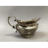 A Victorian silver cream jug of oval outline, fluted with foliate c-scroll handle and vacant