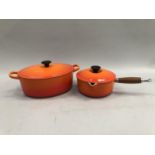 An Le Creuset orange lidded twin handled cook pot together with an orange lidded Le Creuset saucepan