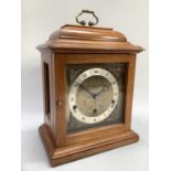 A mahogany cased Elliot bracket clock with a brass carrying handle over a gilt metal dial,