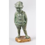 AN ART DECO VERDIGRIS FINISHED METAL FIGURE OF A YOUNG BOY, wearing a feather trimmed hat, jacket