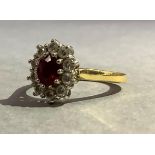 A RUBY AND DIAMOND CLUSTER RING in 18ct yellow and white gold, claw set to the centre with an oval