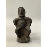 AN ANTIQUE CAST IRON MALE FIGURE, sitting on a stool, his hands on his thighs, his rounded stomach