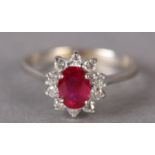 A RUBY AND DIAMOND RING in 18ct gold, the oval faceted ruby claw set and raised against a surround