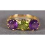 AN AMETHYST AND PERIDOT THREE STONE RING in 18ct gold, the three circular faceted stones claw set in