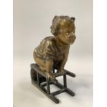 A FRENCH GILT AND PATINATED BRONZE FIGURE OF AN INFANT, on upturned stool, after Juan Clara, with