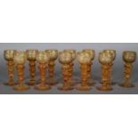 A SET OF TWELVE 19TH CENTURY GERMAN AMBER HOCK GLASSES, the cup-shaped bowls etched with hunting