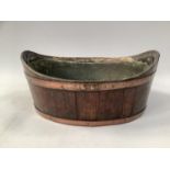 AN OAK AND COPPER BANDED COOPERED PLANT HOLDER, oval, with tin liner, 34cm long x 26.5cm deep x 15.