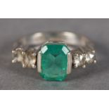 AN EMERALD AND DIAMOND RING in 18ct white gold, claw set to the centre with a step cut emerald,