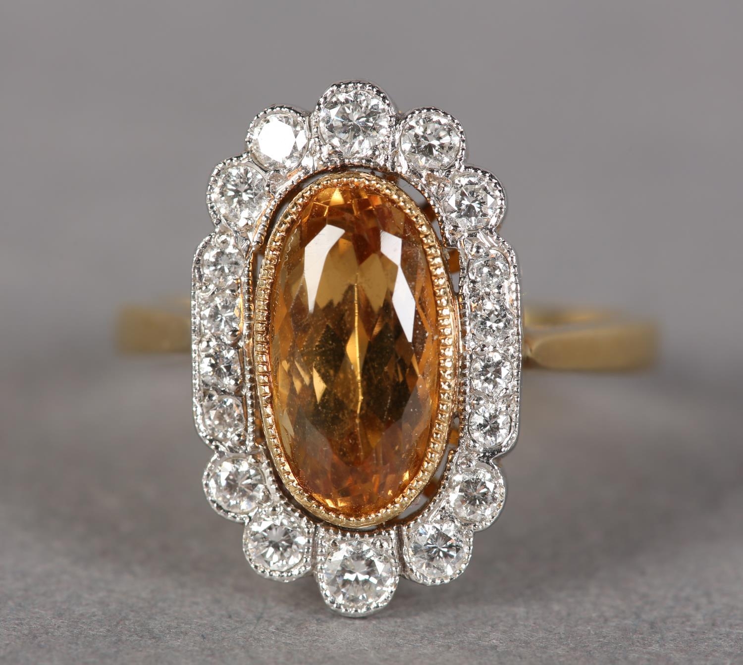 A TOPAZ AND DIAMOND CLUSTER RING in 18ct yellow and white gold, collet set to the centre with an