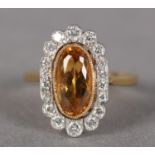 A TOPAZ AND DIAMOND CLUSTER RING in 18ct yellow and white gold, collet set to the centre with an