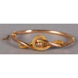 A VICTORIAN STIFF HINGE KNOT BANGLE in 9ct rose gold, the engraved and polished scrolls with an