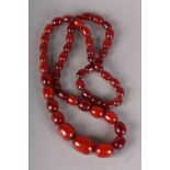 AN EARLY 20TH CENTURY AMBER NECKLACE, the oval graduated beads of dark sherry colour without