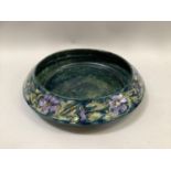 Morrisware shallow dish by George Cartlidge, tube lined and painted with a band of mauve flowers,