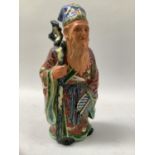A Chinese earthen ware figure of a sage wearing long flowing robe, polychrome glazed and painted