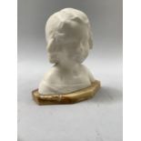 A late 19th/early 20th century alabaster bust of a young girl, her hair in ringlets on a marble