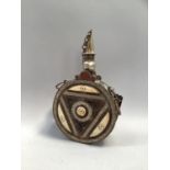 Arabic copper and brass powder flask the frontspiece with raised geometric decoration and inset with