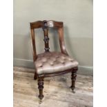 A Victorian spoon back chair with tan leather button seat with turned legs and on brass casters