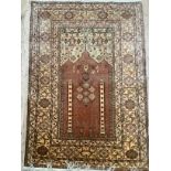 A Persian silk rug, the first in deep salmon, olive green and brown, the field having a prayer niche