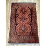 A Middle Eastern rug of fox red, dark brown and camel, the dark brown field filled with three