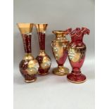 A pair of cranberry and gilt vases with applied flowers together with two further examples, one with