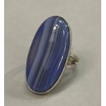 A blue banded agate ring in 9ct white gold C.1978, the stained ova cabochon stone collet set over