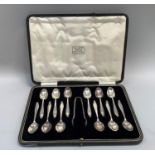 A boxed set of twelve George V silver coffee spoons and sugar tongs, tapered with garlanded