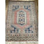 A Middle Eastern rug of salmon, ivory and grey blue, the salmon field having a hooked medallion