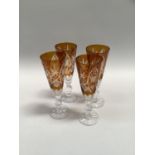 Four amber cut flutes on knop bases, the bowls etched and wheeled, 19cm high