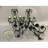 A set of four triple light wall sconces, having three black wrought iron scrolled branches with leaf