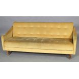 A Studio couch, mid 20th century, in buttoned deep yellow velour, on rounded legs with gilt caps and