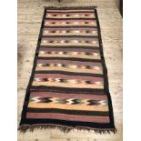 A woven kilim rug worked with geometric bands in orange, red, green and cream on black and brown