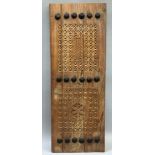 A Middle Eastern hardwood window panel, chip carved with geometric panels between three rows of iron