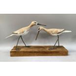 Pair of carved wooden wading birds with string bound legs on a wooden plinth.