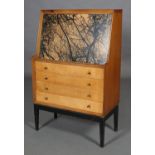 A mid 20th century maple and teak bureau, the fall front with black lithograph print above four