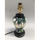 Moorcroft Snowdrop pattern lamp base of baluster form, with cream flowers on green ground on black