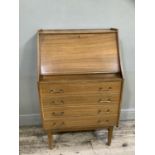 A mid century teak bureau with fold down compartment over four long drawers, brass moulded