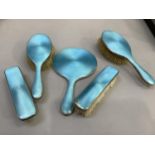 A five piece George V silver and turquoise blue guilloche enamel dressing table set (at fault),