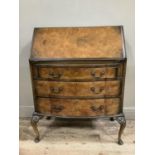 An early 20th century walnut bow fronted bureau, with fall front above three long drawers, brass