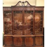 A Christopher Pratt breakfront mahogany bookcase cupboard, having a broken arch and vase pediment,