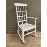 A white painted wooden rocking chair with bobbin and spindle back, on turned legs and with pierced