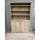 A Victorian stripped pine dresser with four shelves above two door cupboard with three internal