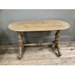 A Victorian beech window table with twin baluster supports and central stretcher on scroll feet with