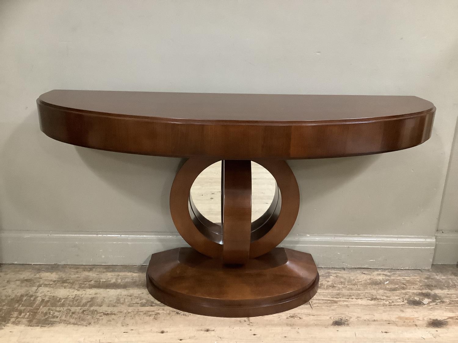 A reproduction console table with support formed of abstract curves and mirrored back, demi-lune