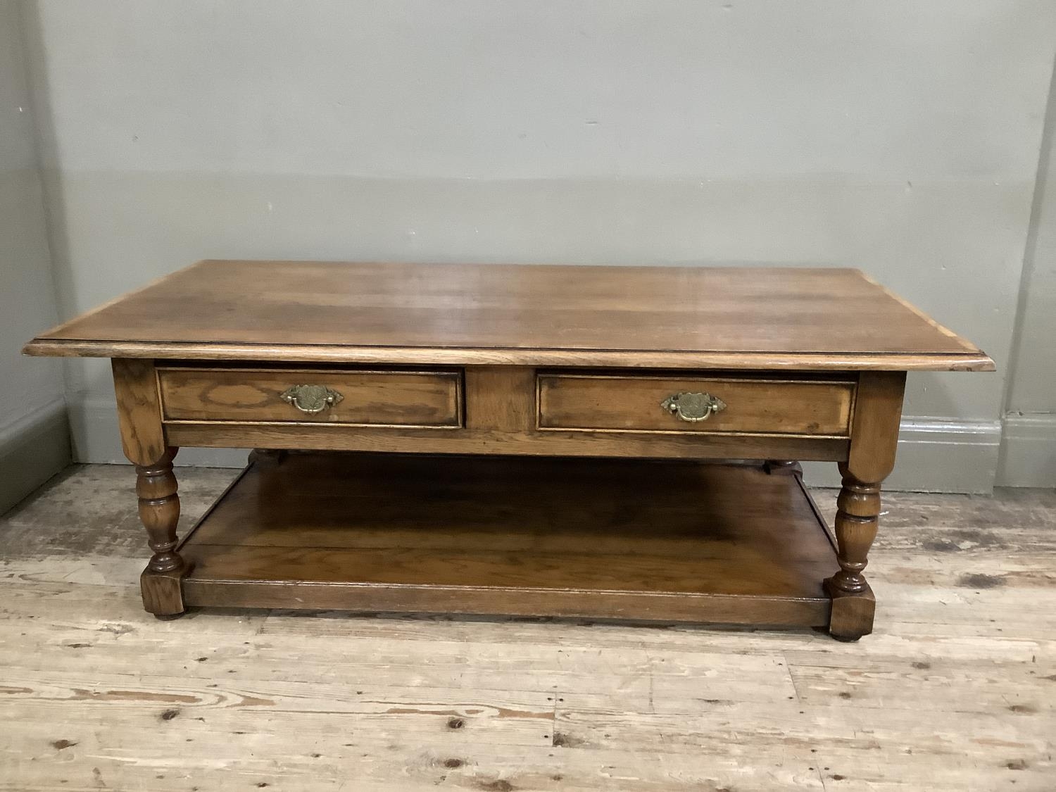 A reproduction oak coffee table, two small drawers, brass handles, on turned supports with under